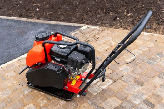 Gasoline Vibrating rammer with a vibrating plate on a construction site. Compaction of the soil before laying paving slabs. tools on the construction site.