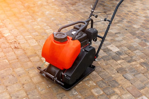 Gasoline Vibrating rammer with a vibrating plate on a construction site. Compaction of the soil before laying paving slabs. tools on the construction site.