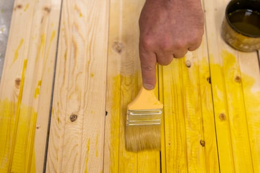 applying the protective composition on the board with a brush. treatment of wood from rotting. the master paints wooden boards.