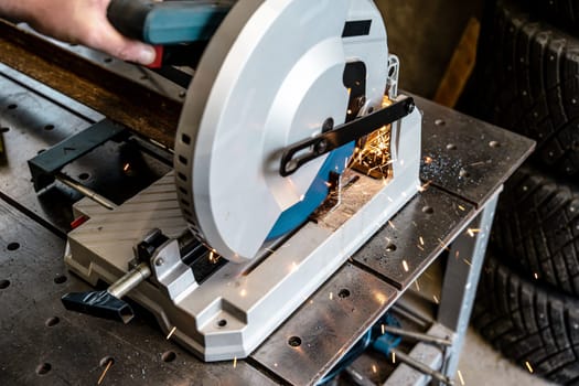 metal saw with tool cutting disc makes a cut. work in home workshop with electric steel cutter machine. Sparks fly from under cutting disc angle grinder. close up.