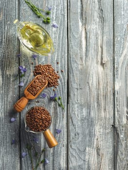 Flax seeds and flax oil. Brown linen seeds and flaxseed oil on old gray wooden background. Copy space. Top view or flat lay. Vertical.