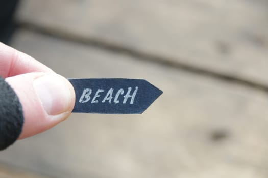 Beach idea. A hand holds a pointer with the inscription beach on a vintage background.