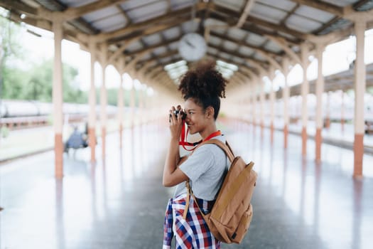 Asian teenage girl african american traveling using a camera take a photo to capture memories while waiting for a train at the station