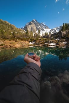 A man with a compass in his hand in the high mountains against the backdrop of a clear lake. Travel concept. landscape photography.