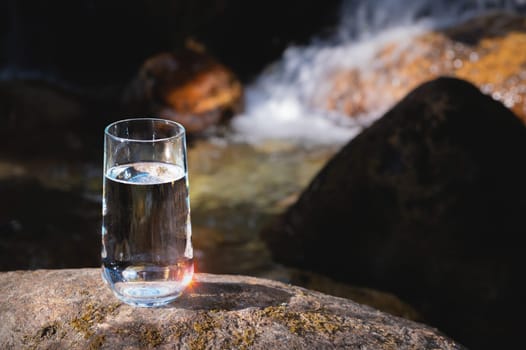 Clean water, healthy concept. Natural drinking water in a glass glass on the background of the nature river.