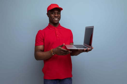 clothing for identity and branding. young handsome american man in red t-shirt and cap working in laptop repair service center.