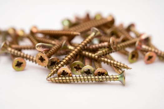 Close-up of universal yellow screws. Self-tapping screws for wood and plastic. Colored self-tapping screws - yellow. Selective focus