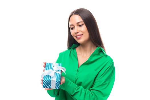 joyful well-groomed brunette long-haired young woman in a green shirt received a gift for her birthday on a white background with copy space.