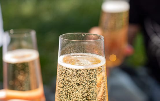 women drinking wine. three glasses white wine in female hands. flute glass of champagne with bubbles outdoors isolated against. garden scene blurred in the background. Cold Beer in glass. outdoor