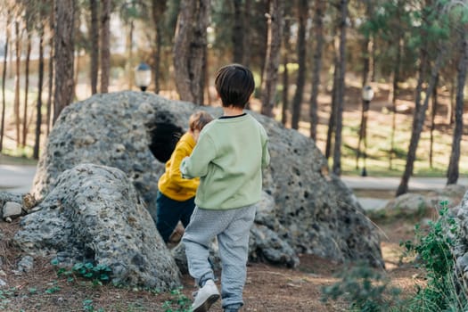 School boys kids playing travel outside in the forest. Siblings brothers children taking a hike in the rocky boulder forest city park.