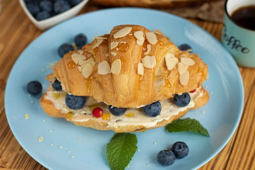 Croissant sandwich with cheese , arugula and berries. classic american breakfast. french croissant with fresh berries. blueberry strawberry on cream cheese. Croissant and cup coffee. aesthetic dessert