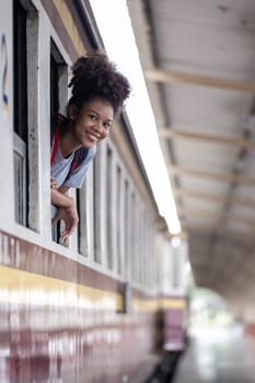 Young asian travel by train sticking her head out of the train, Happy smiling woman female girl looks out from train window travelling by train. High quality photo