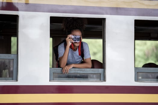 Young asian travel by train sticking her head out of the train, Happy smiling woman female girl looks out from train window travelling by train. High quality photo