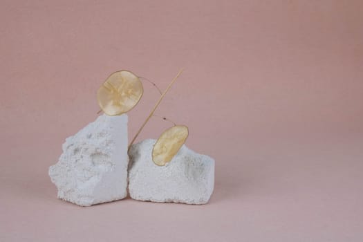 Podium made of white stone with dried flowers on a pink background. Product installation: slabs of broken stone, platform of white stone, placement of objects made of blocks with rough texture