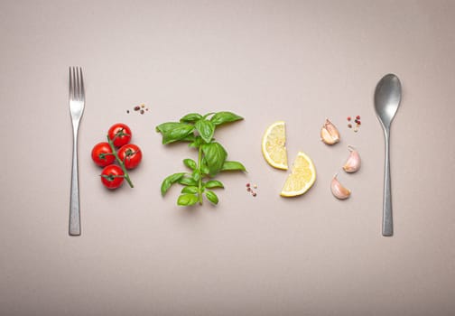 Composition with branch of fresh cherry tomatoes, basil branch, garlic cloves, lemon wedges, kitchen spoon and fork on minimalistic gray clean background, overhead shot
