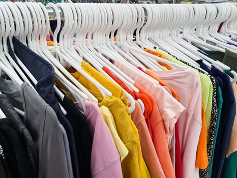 Old clothes are hung on hangers in a second-hand store.