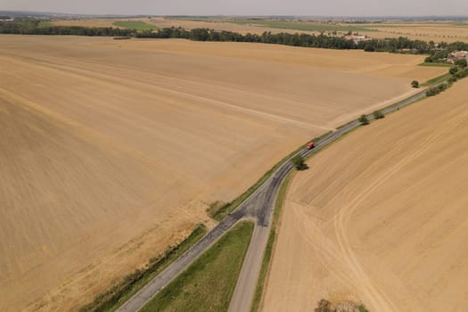 View from top of fields from which wheat is harvested, road between fields for passage of combine harvesters and tractors.