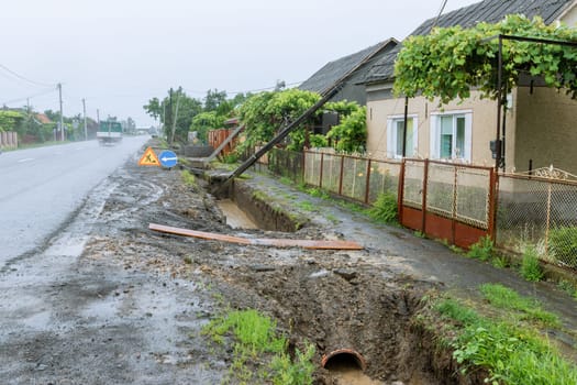 As a result of heavy rain , several electric poles collapsed onto people's fences. Excessive water levels have weakened the foundations of electric poles.