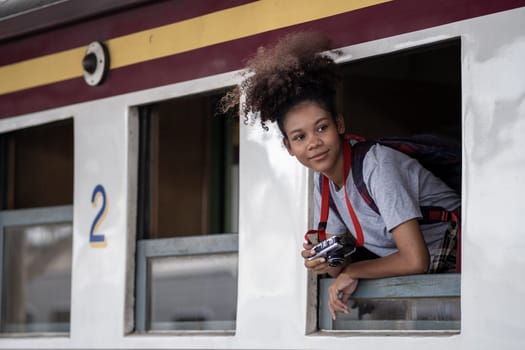 Young asian travel by train sticking her head out of the train, Happy smiling woman female girl looks out from train window travelling by train. High quality photo