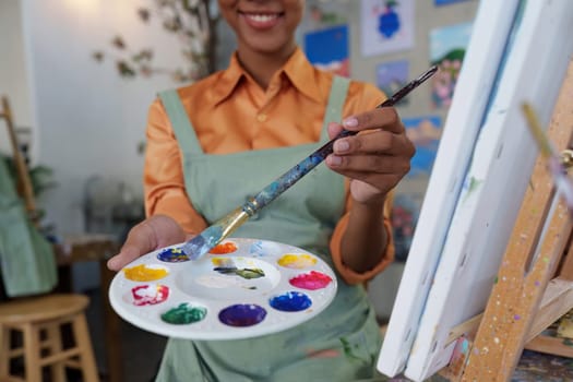 Beautiful american african artist woman painting in art studio at the university classroom.