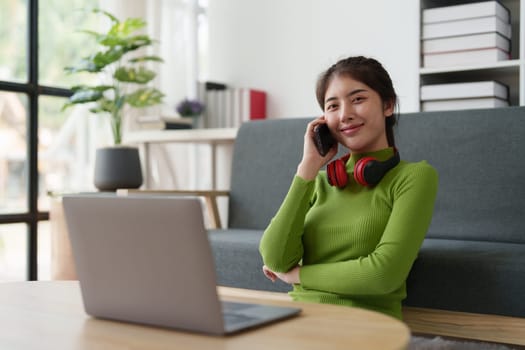 Young asian relaxed smiling pretty woman relaxing with mobile phone at home. Female feeling joy enjoying with mobile phone on cozy couch.