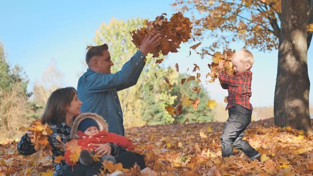 A happy family in an autumn park having fun and crumbling leaves