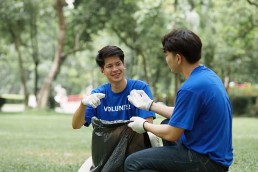 Young Asian Volunteers with garbage bags cleaning park area. Ecology, Charitable organization concept.