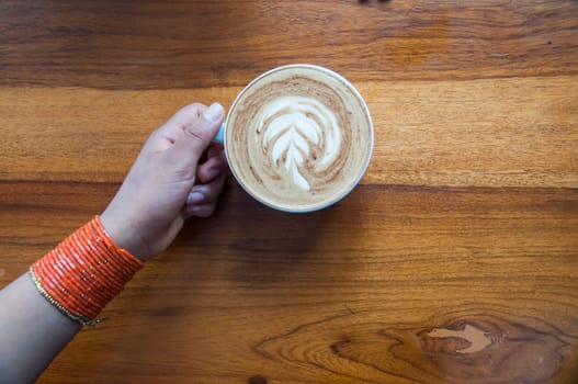 horizontal composition of an arm of an indigenous girl holding a cup of coffee. High quality photo