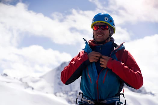 A man in special mountaineering glasses with a mirror-effect orange color, takes care of his eyesight and safety in the snowy mountains. The hiker travels in the mountains, is engaged in climbing.