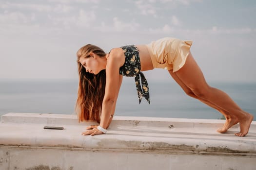 Woman park yoga. Side view of free calm bliss satisfied woman with long hair standing in morning park with yoga position against of sky by the sea. Healthy lifestyle outdoors in park, fitness concept