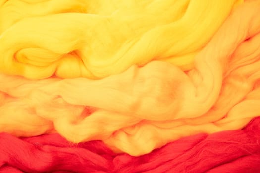 Yellow, beige and red merino wool for felting as background texture.