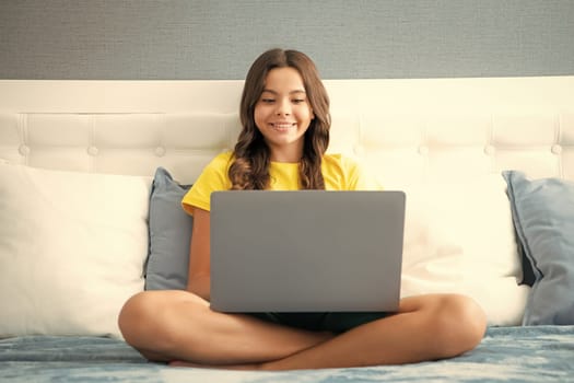 Young teenage girl, little student studying virtual course, learning distance class taking web training, looking at laptop computer watching online video lesson on bed at home