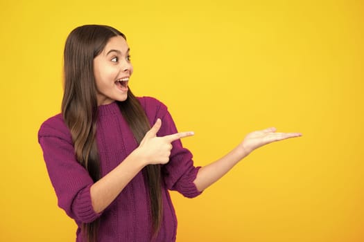 Wow, it's unbelievable. Shocked teenager child pointing aside at copy space. Teen girl pointing with two hands and fingers to the side