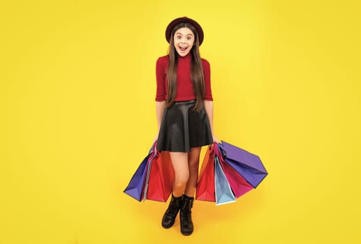 Happy teenager portrait. Funny teen girl hold shopping bag enjoying sale isolated on yellow. Portrait of teenager schoolgirl is ready to go shopping. Smiling girl