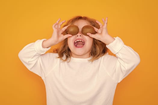 Child hold kiwi in studio. Kiwi fruit. Studio portrait of cute kid boy with kiwi isolated on yellow