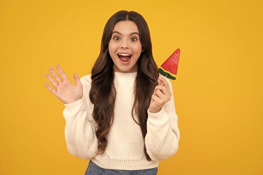 Funny child with lollipop over yellow isolated background. Sweet childhood life. Teen girl with yummy caramel lollipop, candy shop. Excited teenager girl