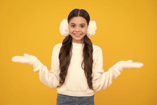 Modern teen girl wearing sweater and winter warm earmuff ear-flaps on isolated yellow background. Happy face, positive and smiling emotions of teenager girl