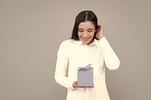 Happy birthday. Woman holding gift box with ribbon. Studio portrait over gray background