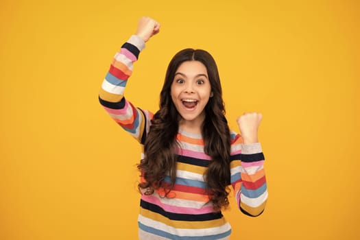 Amazed teenager. Child girl rejoicing, say yes, looking happy and celebrating victory, champion gesture, fist pump, on yellow background. Excited teen girl