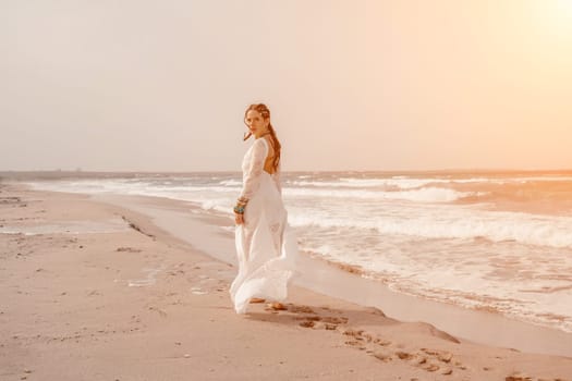 woman sea white dress. Model in boho style in a white long dress and silver jewelry on the beach. Her hair is braided, and there are many bracelets on her arms