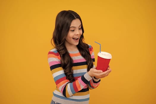 Teenage girl with take away cup of cappuccino coffee or tea. Child with takeaway cup on yellow background, morning drink beverage. Happy teenager, positive and smiling emotions of teen girl