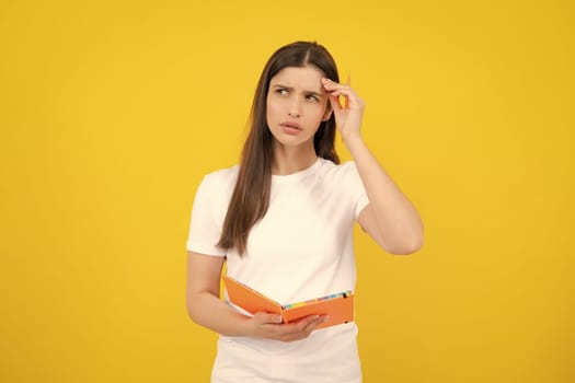 Young student girl in casual clothes, isolated on yellow background studio portrait. Hold notebooks. Cheerful young attractive student woman