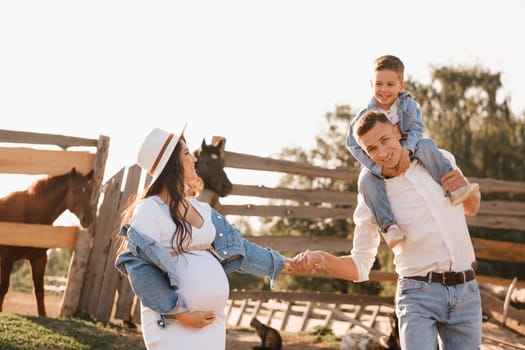 Happy family near horses at a farmer's ranch at sunset.