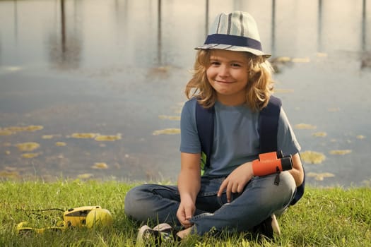 Happy child playing with binoculars. Explore and adventure. Child boy with backpacks exploring nature and environment. Outdoor leisure activity for children. Summer journey for tourist