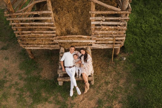 A stylish family in the countryside at sunset. A pregnant woman with her husband and son in nature.