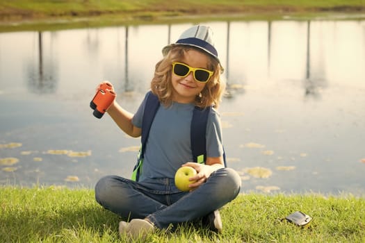 Little child with backpack and binoculars. Imagination or exploration in park. Happy child playing with binocular. Young tourist explorer. Child vacation and travel. Summer journey for kids