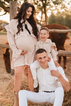 Happy family near horses at a farmer's ranch at sunset.