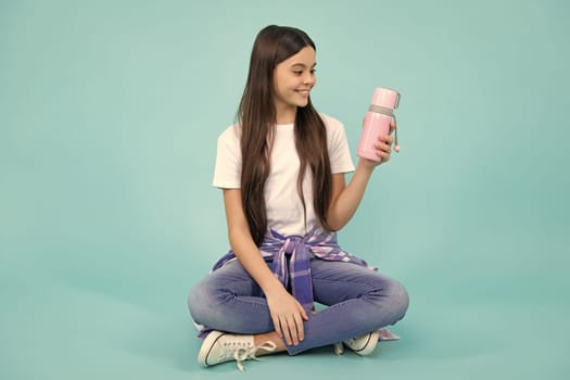 12, 13, 14 year old girl holds thermos and mug of hot tea. Happy teenager, positive and smiling emotions of teen girl