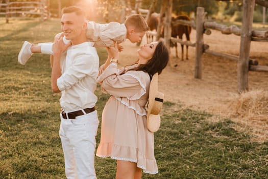 A stylish family in the countryside at sunset. A pregnant woman with her husband and son in nature.