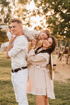 A stylish family in the countryside at sunset. A pregnant woman with her husband and son in nature.